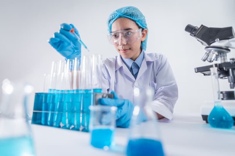 A young woman scientist performing experiments on blue chemicals