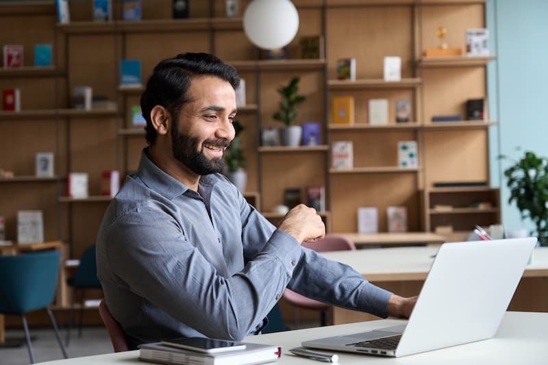 A smiling man using a laptop