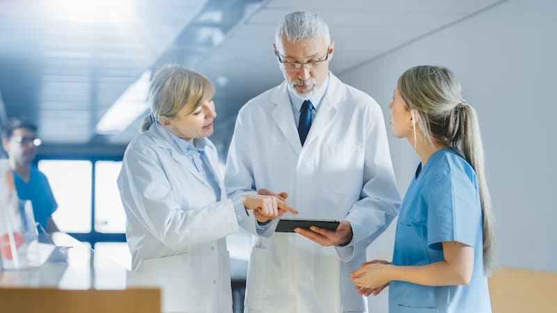 Two doctors and a nurse discussing information on a tablet
