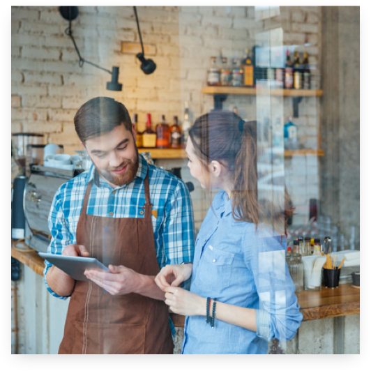 Two coffeeshop employees discussing information on a tablet.